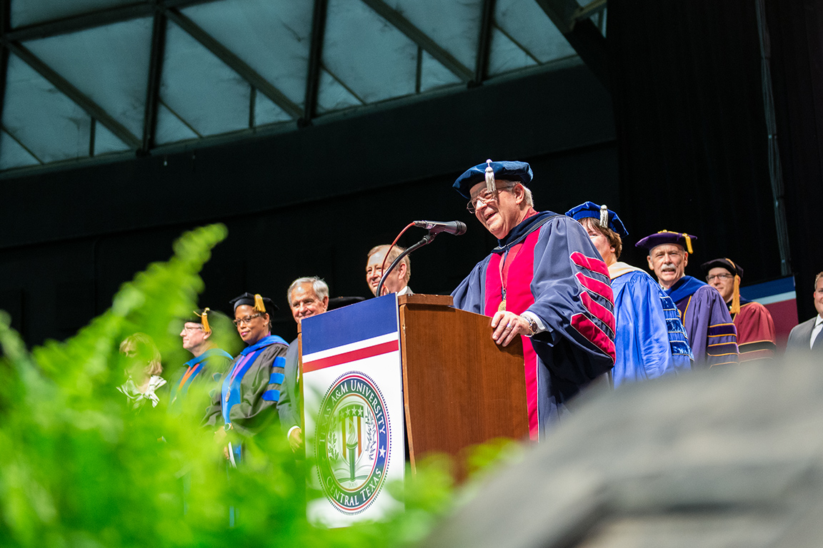 Dr. Marc presenting at a podium during graduation