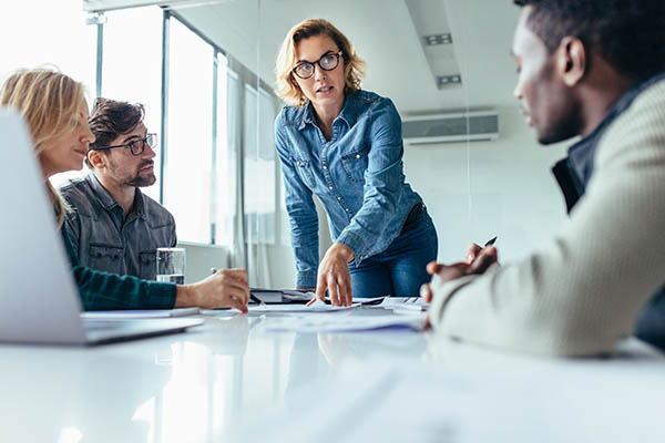 A female professional reviewing information with two male professionals