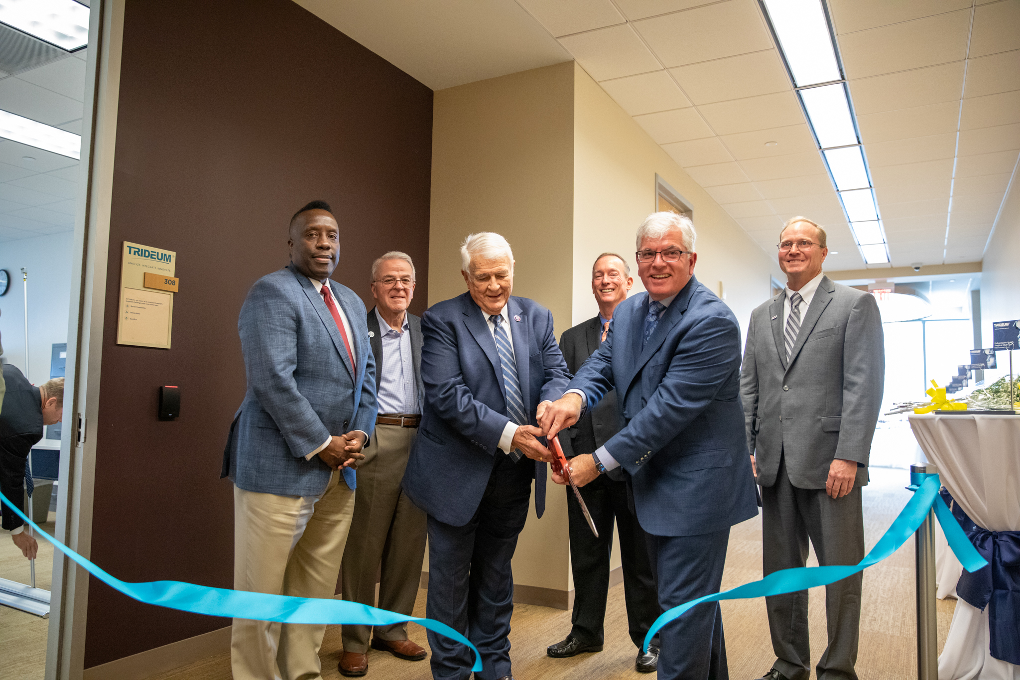 Trideum CEO and COO cut the ribbon in front of their campus office