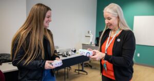 Student Taylor O'Donnell and Dr. Elizabeth Casey speaking while holding floor robots