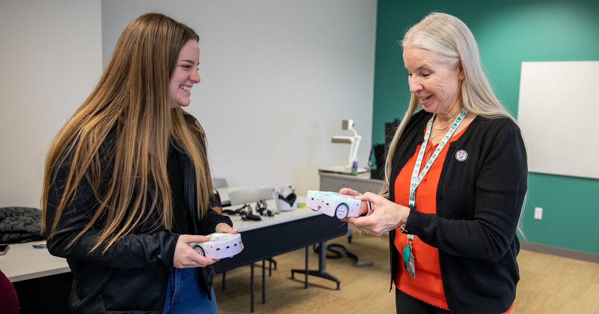 Student Taylor O'Donnell and Dr. Elizabeth Casey speaking while holding floor robots