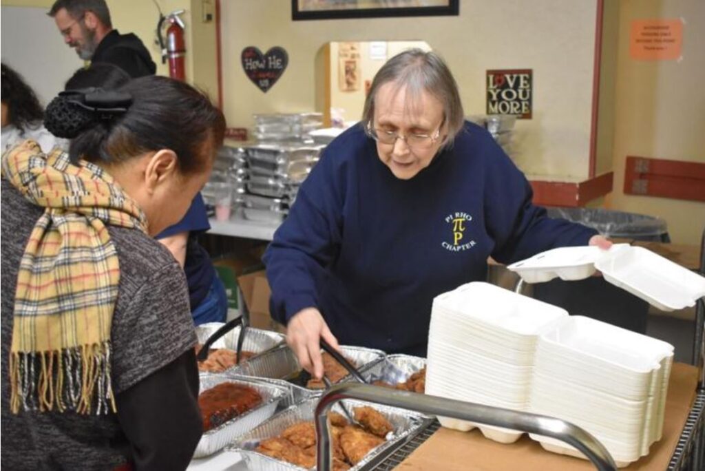 Claudia Rappaport putting fried chicken into a to-go box for the person in front of her.