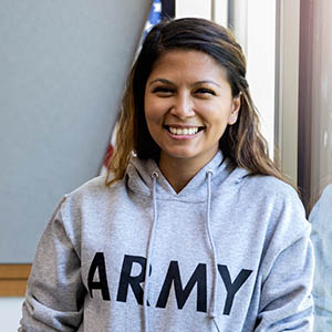 Female army vet leans against window and smiles for camera