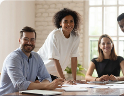 Three smiling adults at a table with notepads and papers.