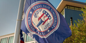 A blue flag waving with the TAMUCT crest on it