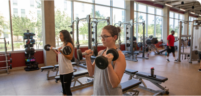 Two students lifting weights in the campus gym.
