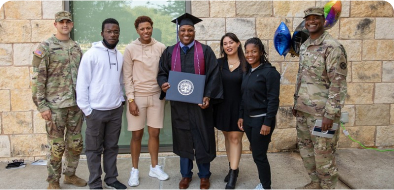 Seven people smiling at the camera, in celebration of the male student in the middle receiving his degree/diploma.