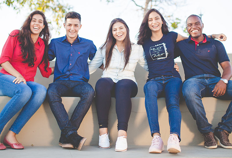 Young adults sitting together with their arms around each other