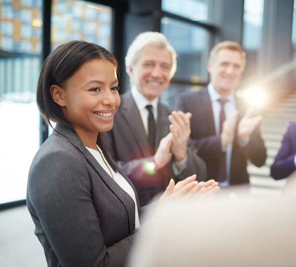 Multiple people in suits clapping and smiling