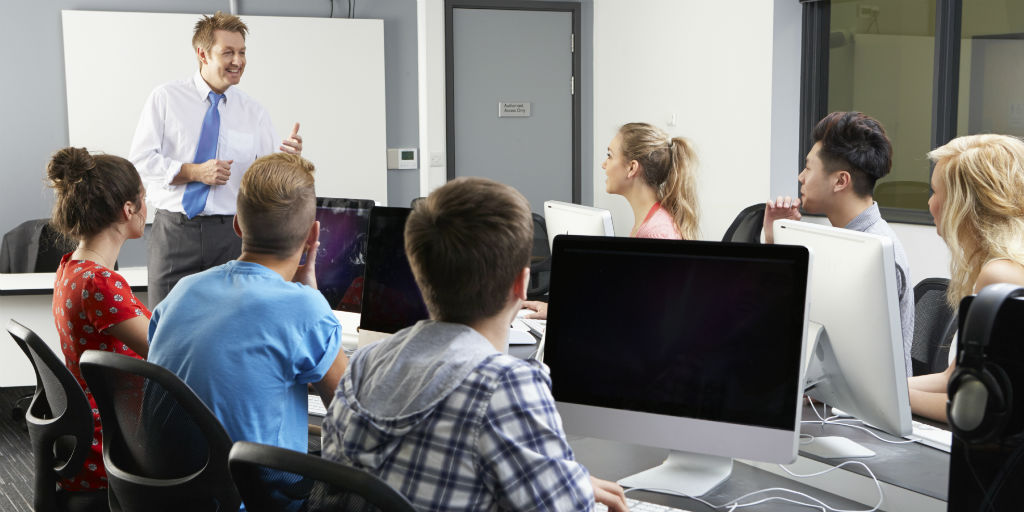 A man talking to a room of people at computers