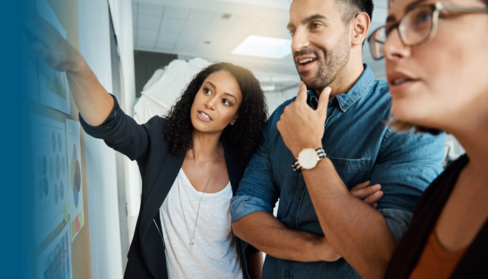 3 people examining a board with information on it