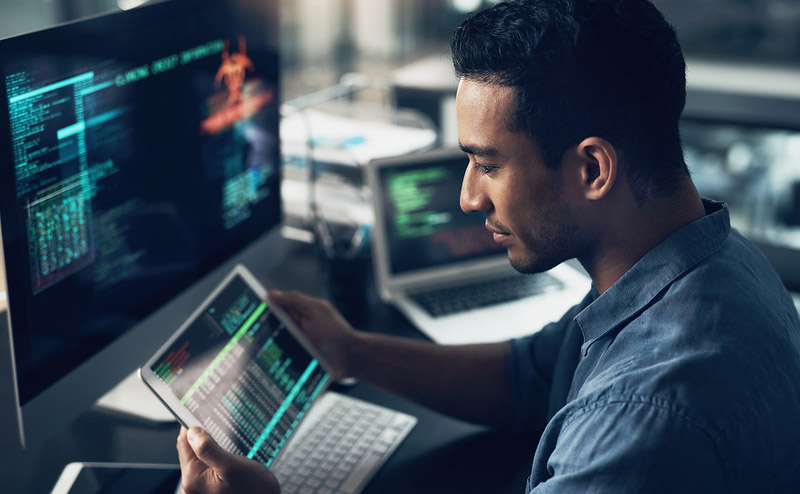 Man staring at a tablet in front of a computer
