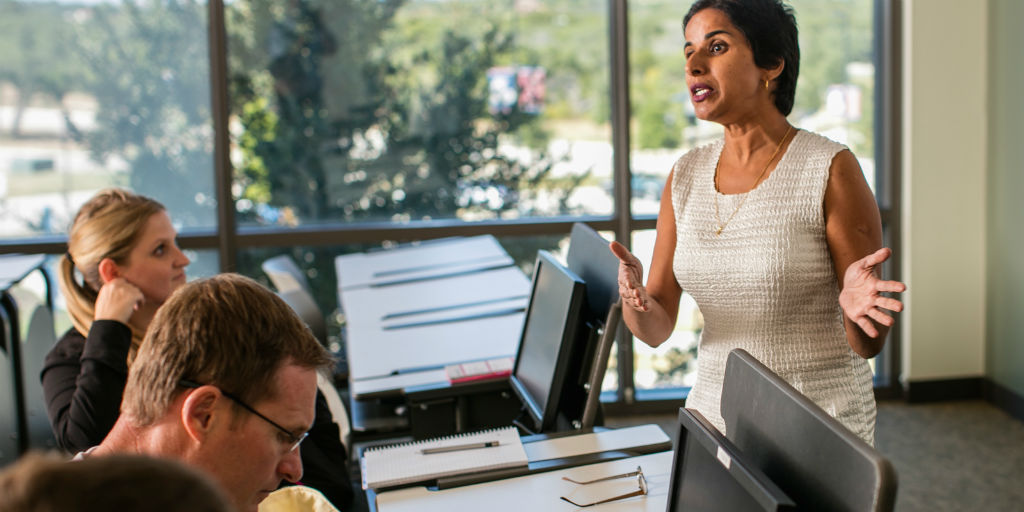 A woman talking to a group of students at computers