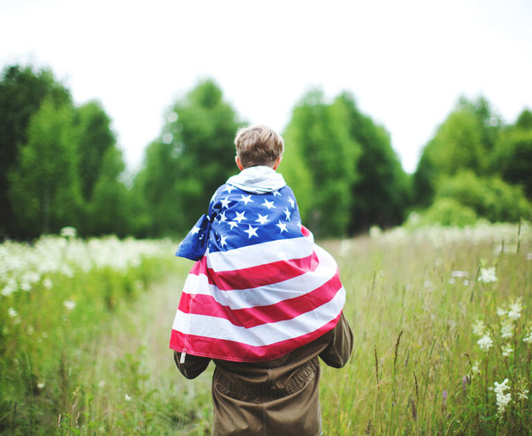 Image of father and son. Son is wrapped in American flag.