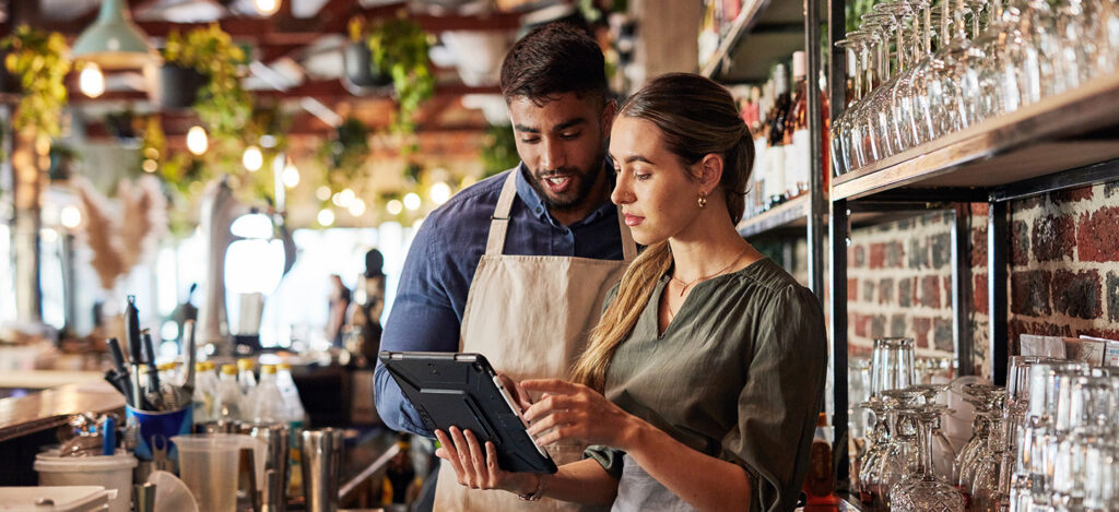 Two small business owners review records on a mobile device.
