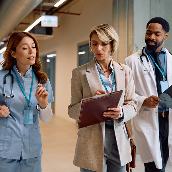 Photo of senior nursing administrator walking with two other healthcare professionals.