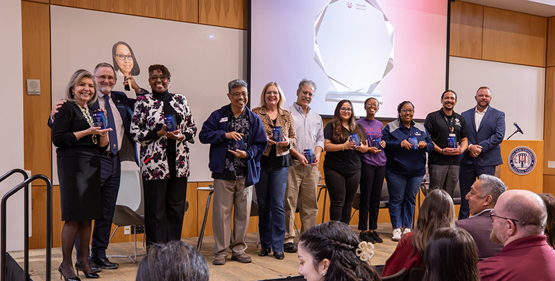 12 employees lined up on stage after being recognized for receiving staff appreciation awards.