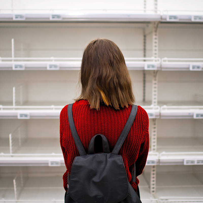 Woman staring at empty grocery shelves