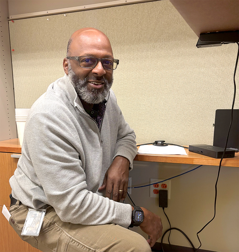 Man kneeling by a computer outlet.