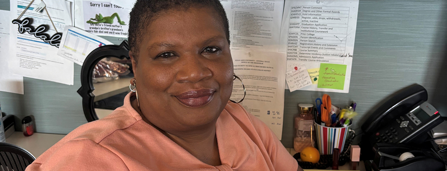 Amelia Smith, a black woman in a peach colored blouse, sitting in her office.