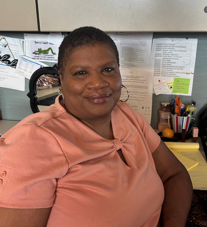 Amelia Smith, a black woman in a peach colored blouse, sitting in her office.