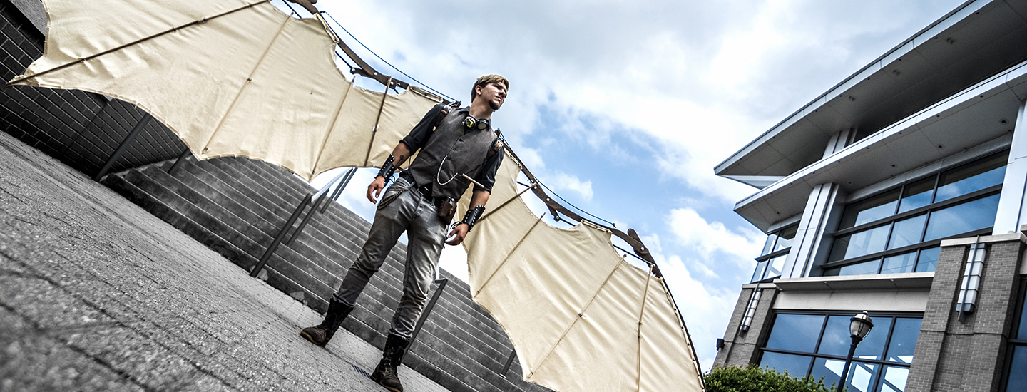 A man standing in a courtyard wearing mechanical wings.