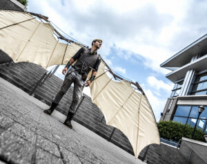 A man standing in a courtyard wearing mechanical wings.