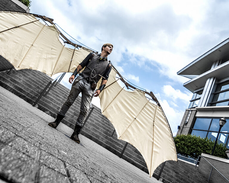 A man standing in a courtyard wearing mechanical wings.