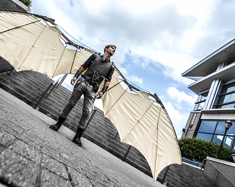 A man standing in a courtyard wearing mechanical wings.
