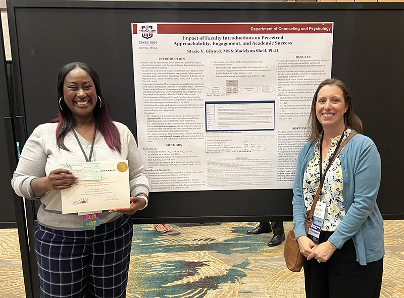 Two women standing on either side of an academic research poster.