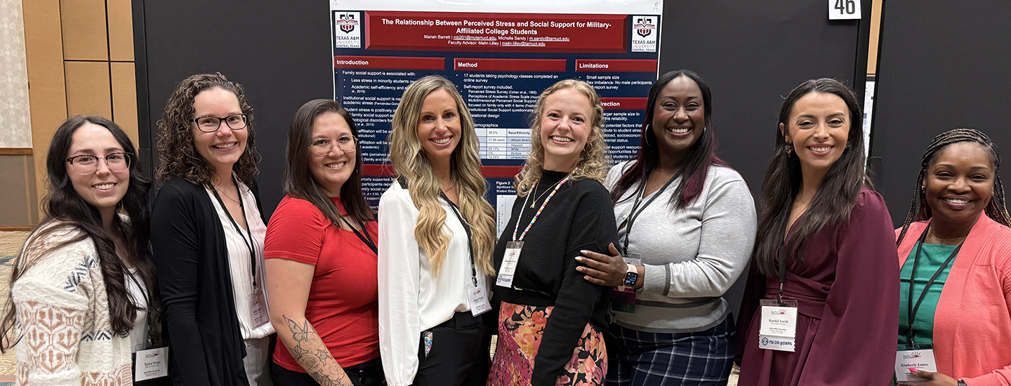 A group of 8 women lined up in front of an academic research poster.