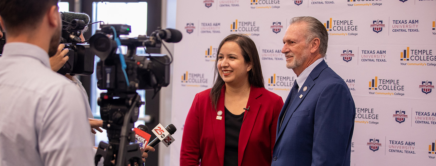 A man and woman stand in front of a step-and-repeat banner with Temple College and A&M–Central Texas logos displayed. They are answering questions from the media.