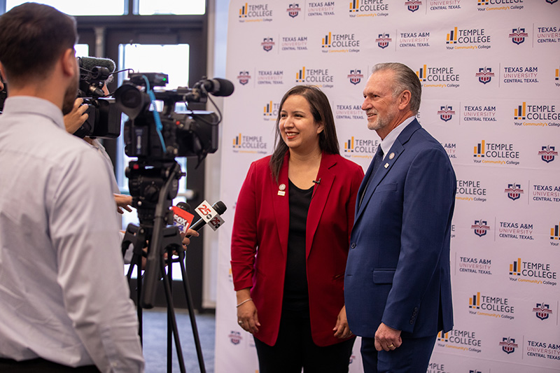 A man and woman stand in front of a step-and-repeat banner with Temple College and A&M–Central Texas logos displayed. They are answering questions from the media.