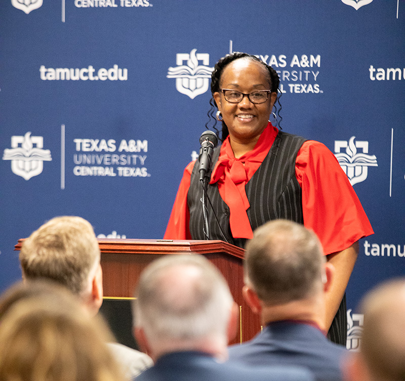 Dana Mobley standing at a podium, talking to a crowd.