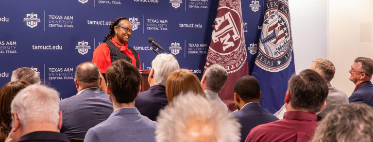 Dana Mobley standing at a podium, talking to a crowd.