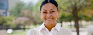 Young woman, Nadine Tochi, smiling at the camera wearing a white blouse and sweater vest.