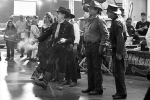 A group of people dressed in Western costumes at an indoor themed event, showcasing historical attire.