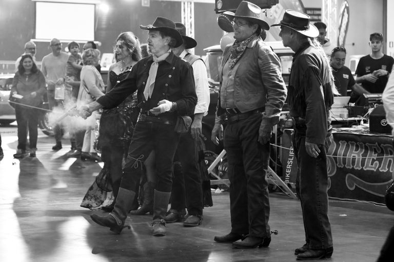 A group of people dressed in Western costumes at an indoor themed event, showcasing historical attire.
