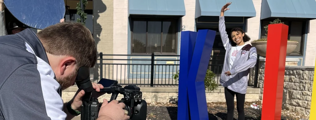 Young woman stands as the I in Killeen while being filmed.