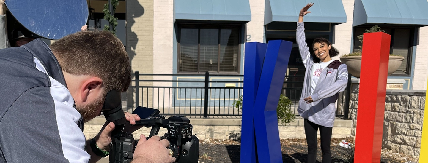 Young woman stands as the I in Killeen while being filmed.