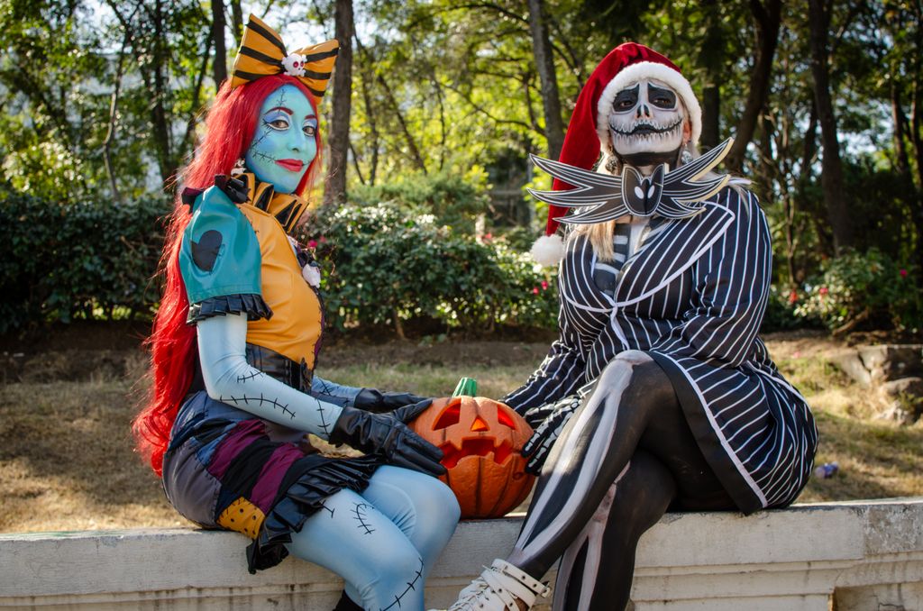 Two people in creative Halloween costumes inspired by a well-known fantasy film sit outdoors with a pumpkin.